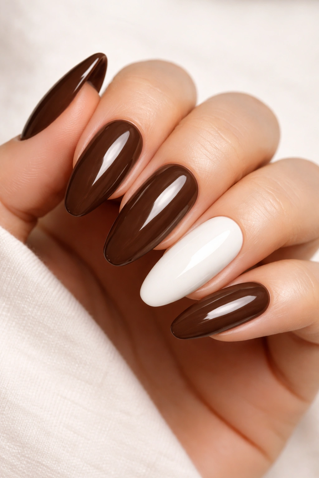 Close-up of chocolate brown nails with a single white accent nail