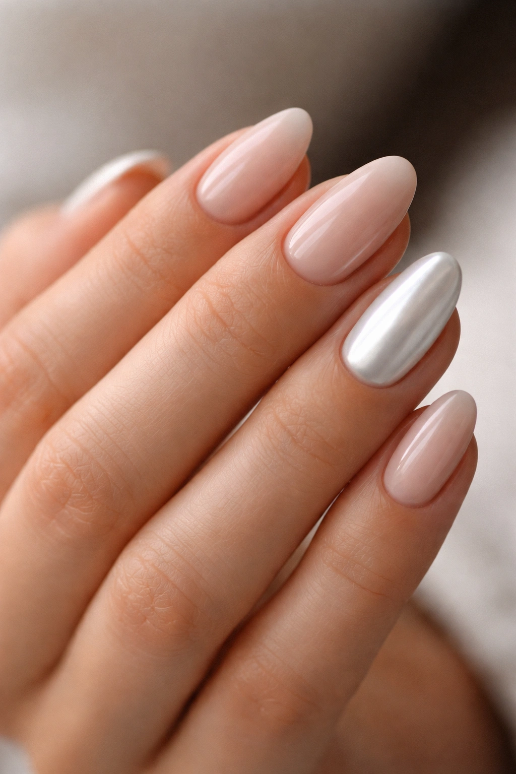 Close-up of short almond nails with mixed nude and white chrome accents