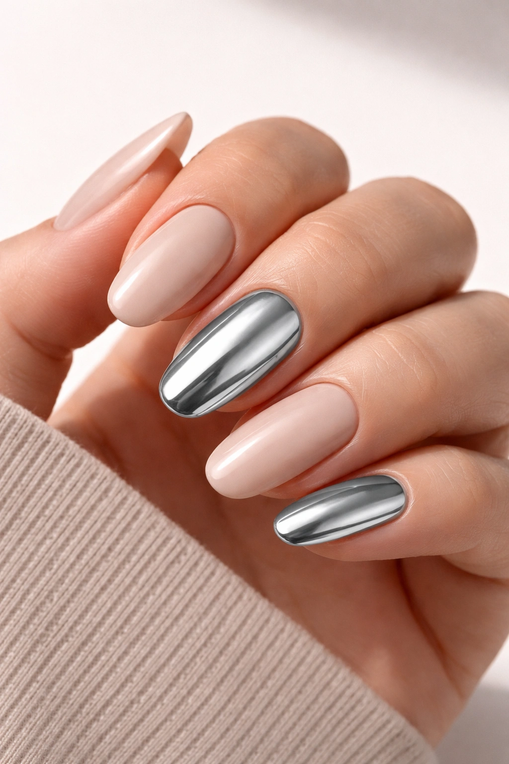 Close-up of hand showing chrome accent nails on a nude base