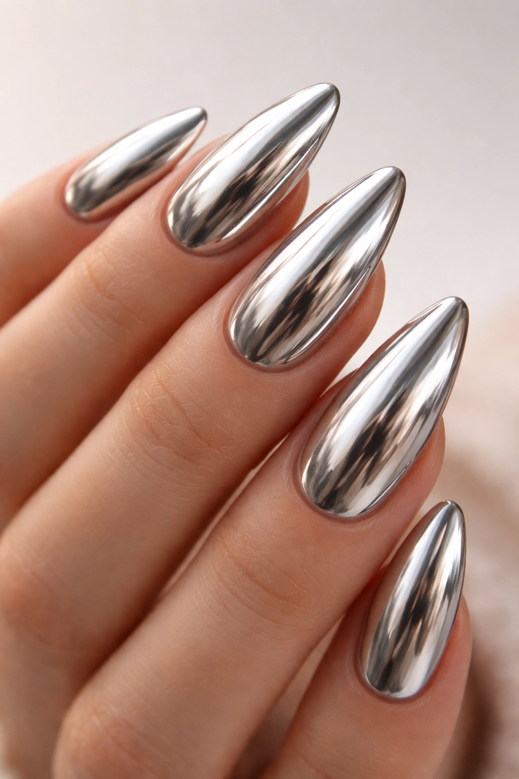 Close-up of almond-shaped chrome metallic acrylic nails.