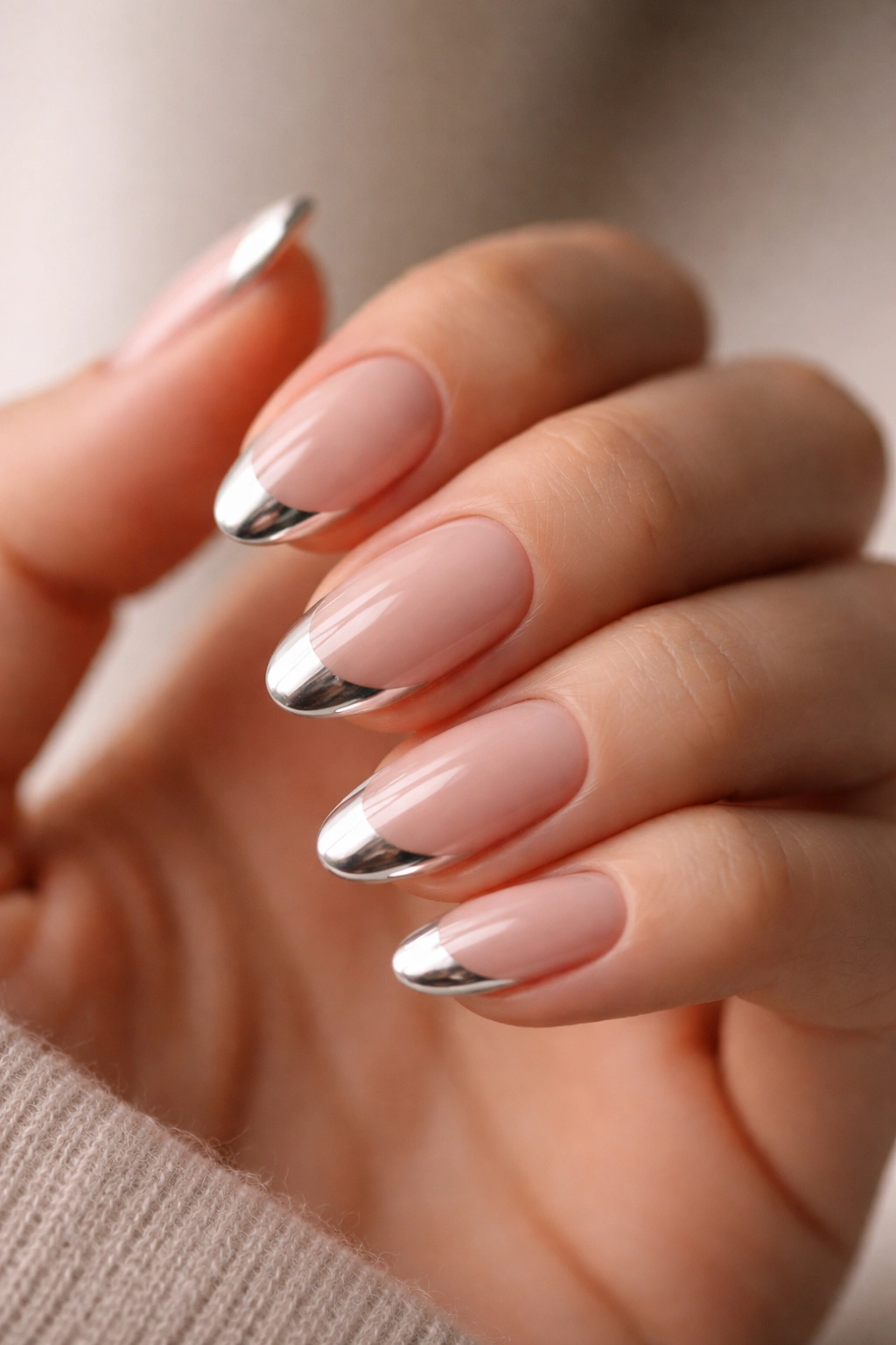 Close-up of short almond nails with nude base and silver chrome French tips