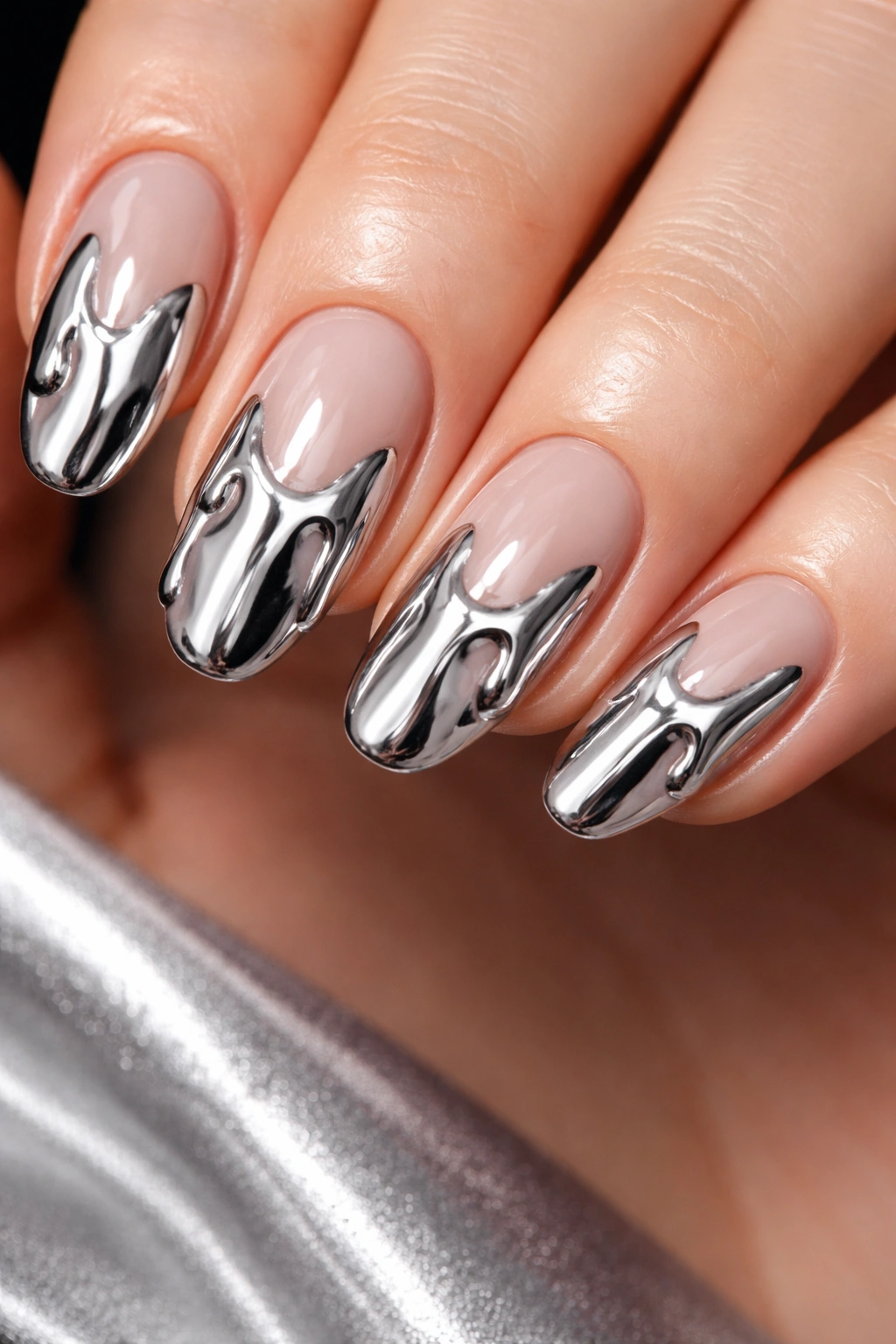 Close-up of chrome drip nails with reflective chrome drips on a neutral base.