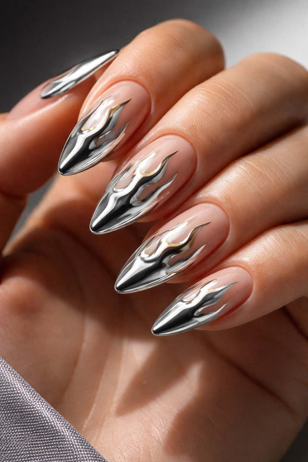 Almond-shaped nails with chrome flame tips rising from the nail tips