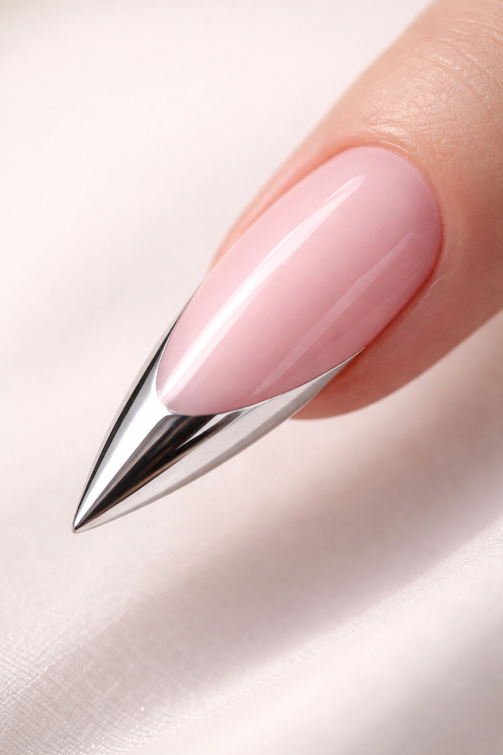 Close-up of a stiletto nail with a mirror chrome tip and pink base