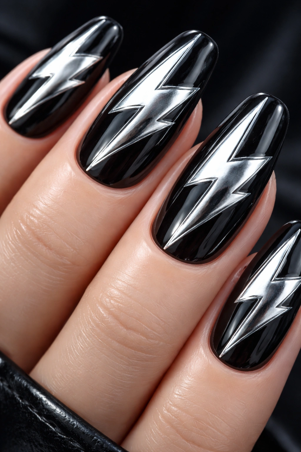 Close-up of nails with bold chrome lightning bolts on a dark base