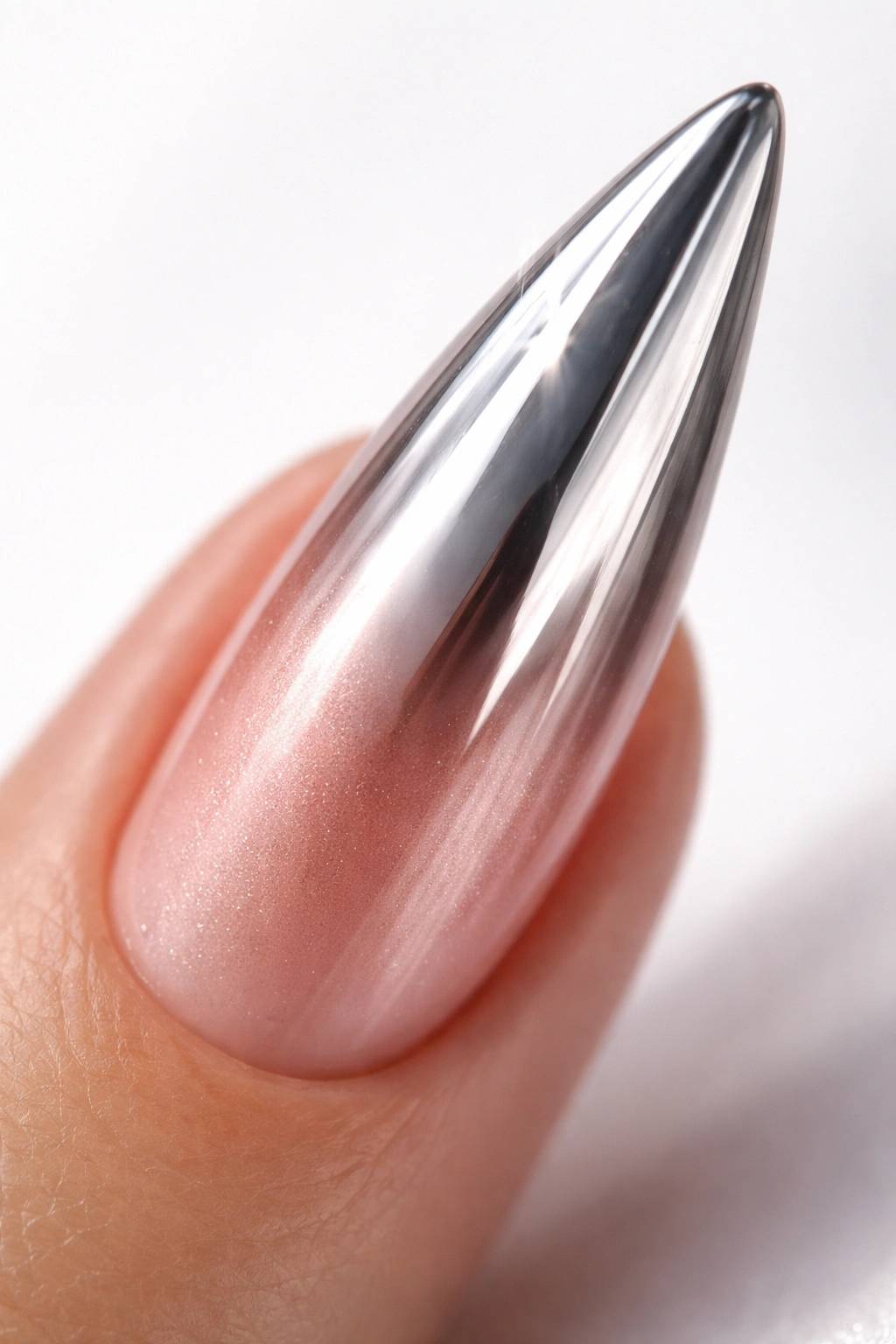 Close-up of a stiletto nail with chrome mirror finish and rose gold ombre, studio lighting