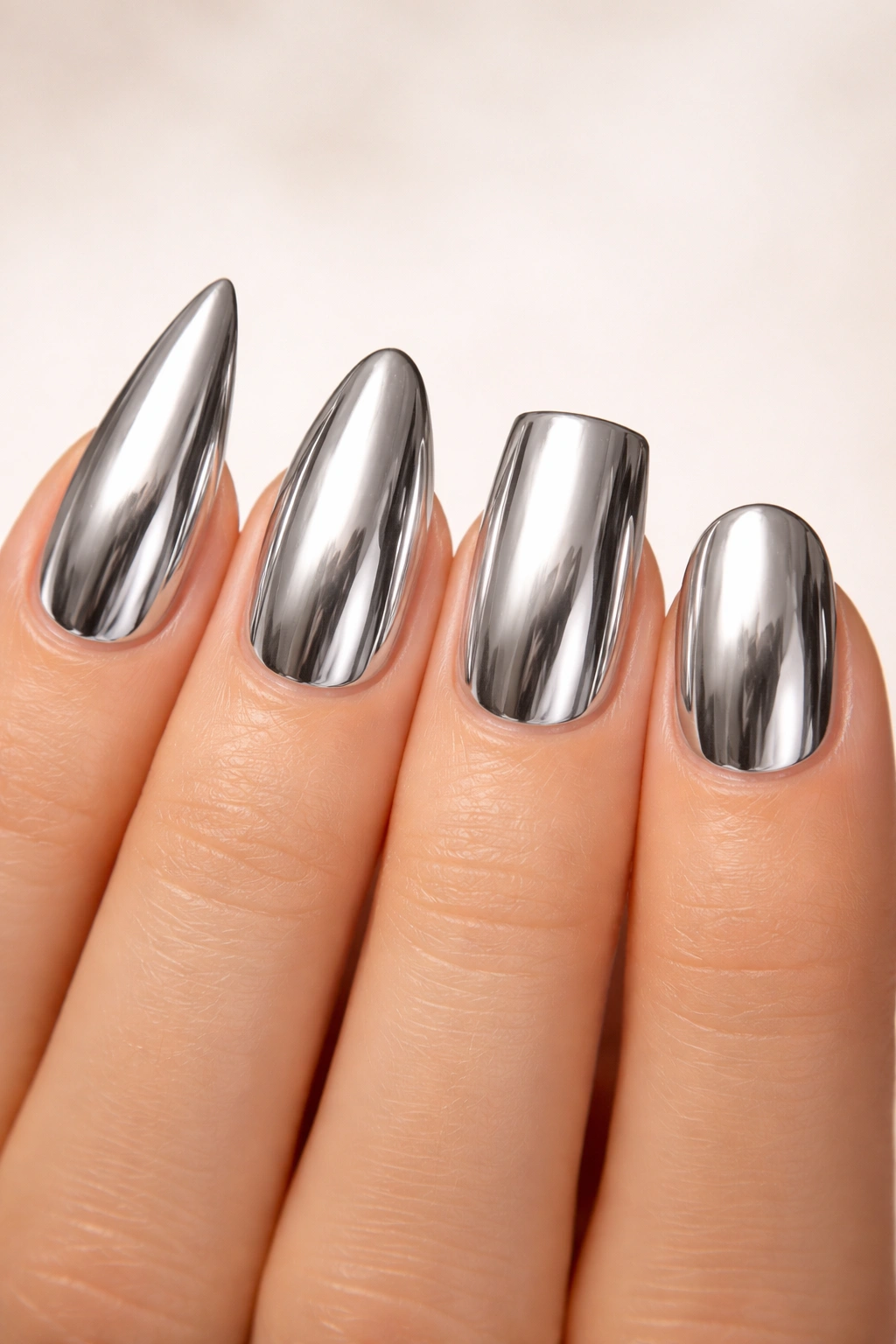 Hand with chrome nails showing stiletto, almond, square, and short rounded shapes