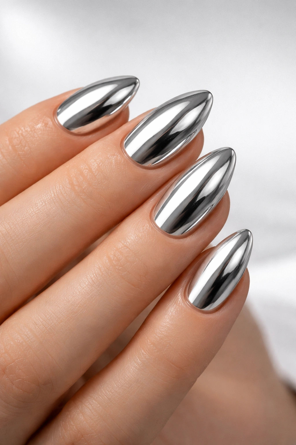 Close-up of short almond nails with chrome mirror finish.