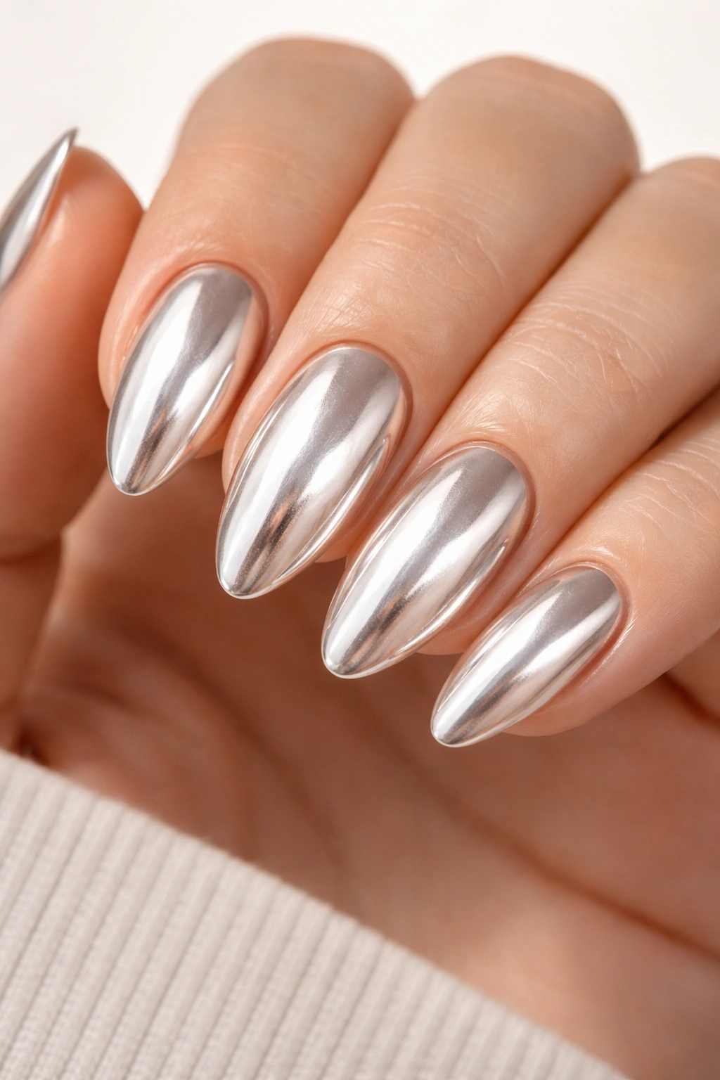 Close-up of chrome almond oval nails with reflective metallic finish