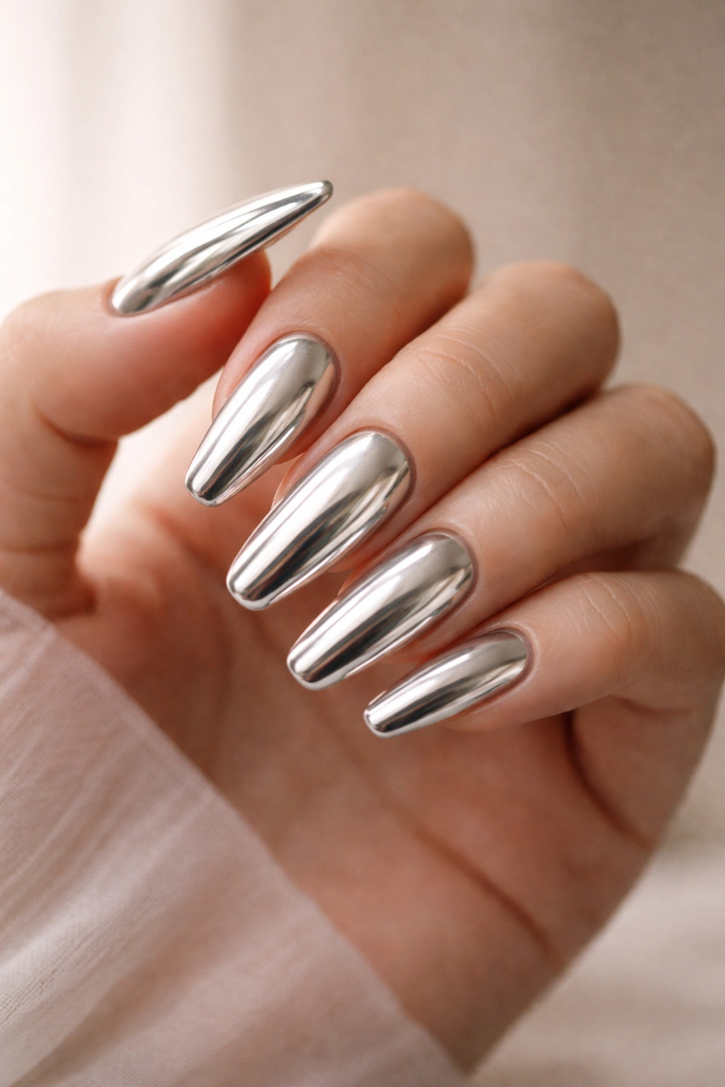 Close-up of chrome ballerina nails with mirror-like finish on moisturized hands