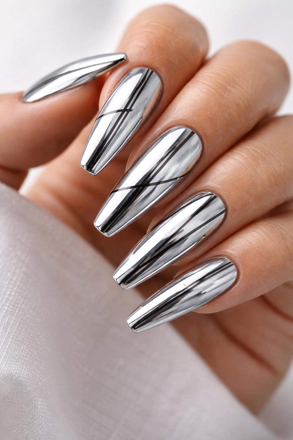 Chrome coffin nails with ultra-thin black linear accents on a bare hand
