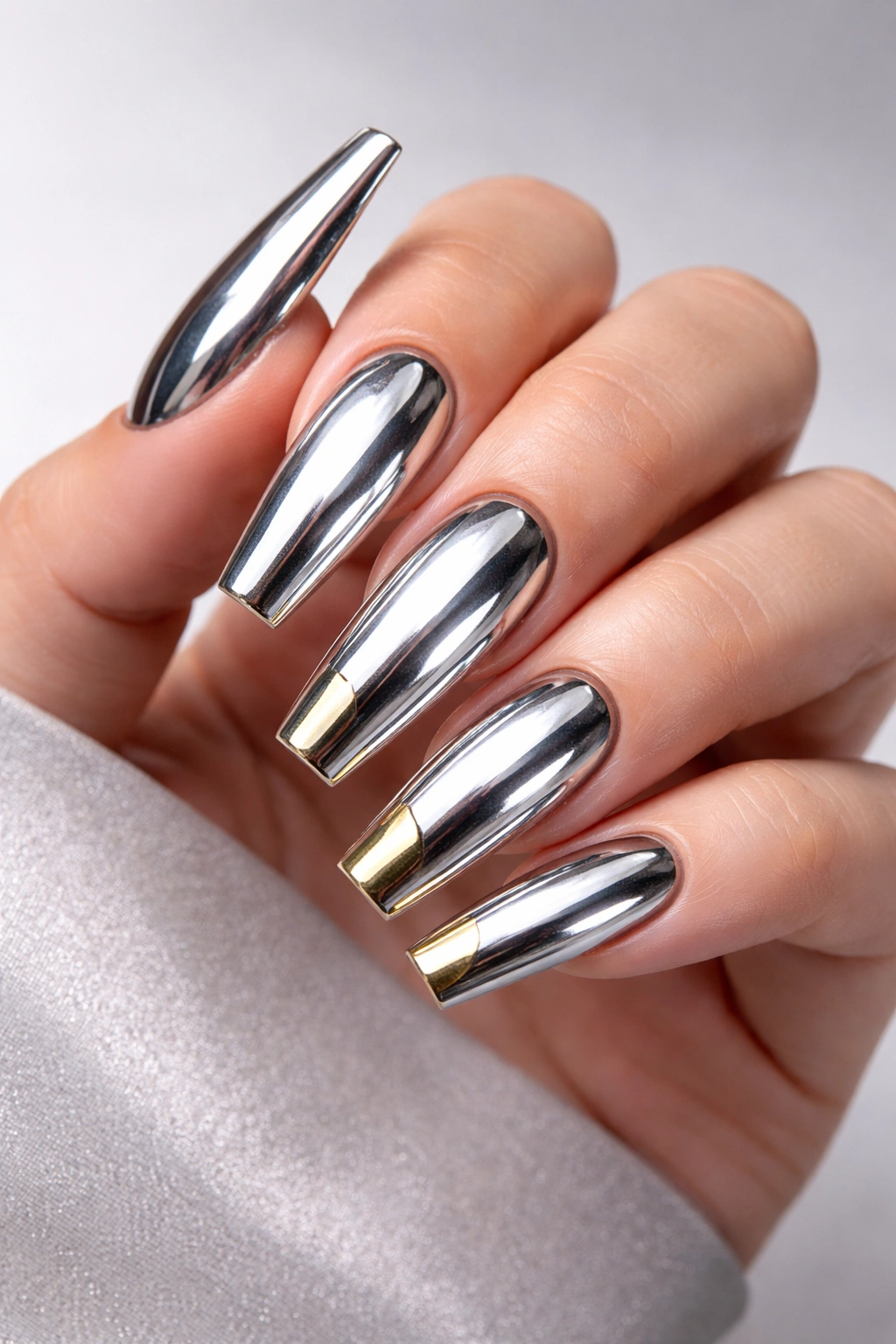 Close-up of chrome coffin nails on a bare hand with a mirror-like finish