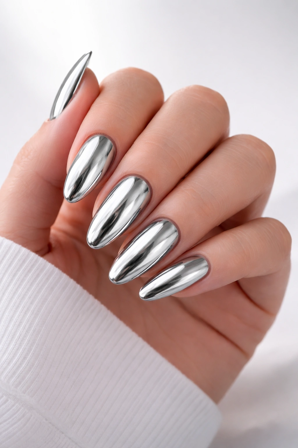 Close-up of finished silver chrome nails on hand with reflective metallic finish