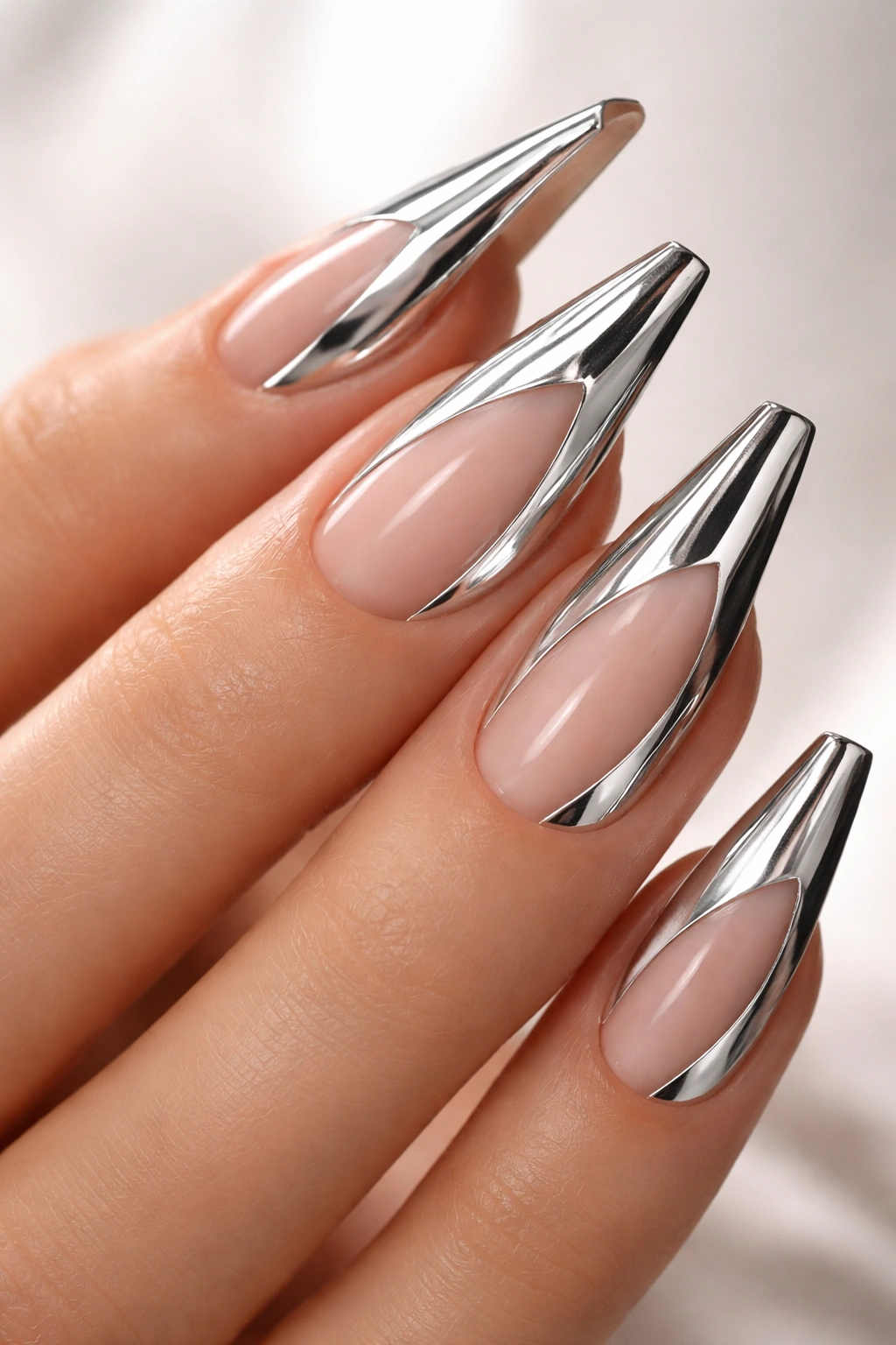 Close-up of reverse stiletto nails with nude base and chrome cutouts