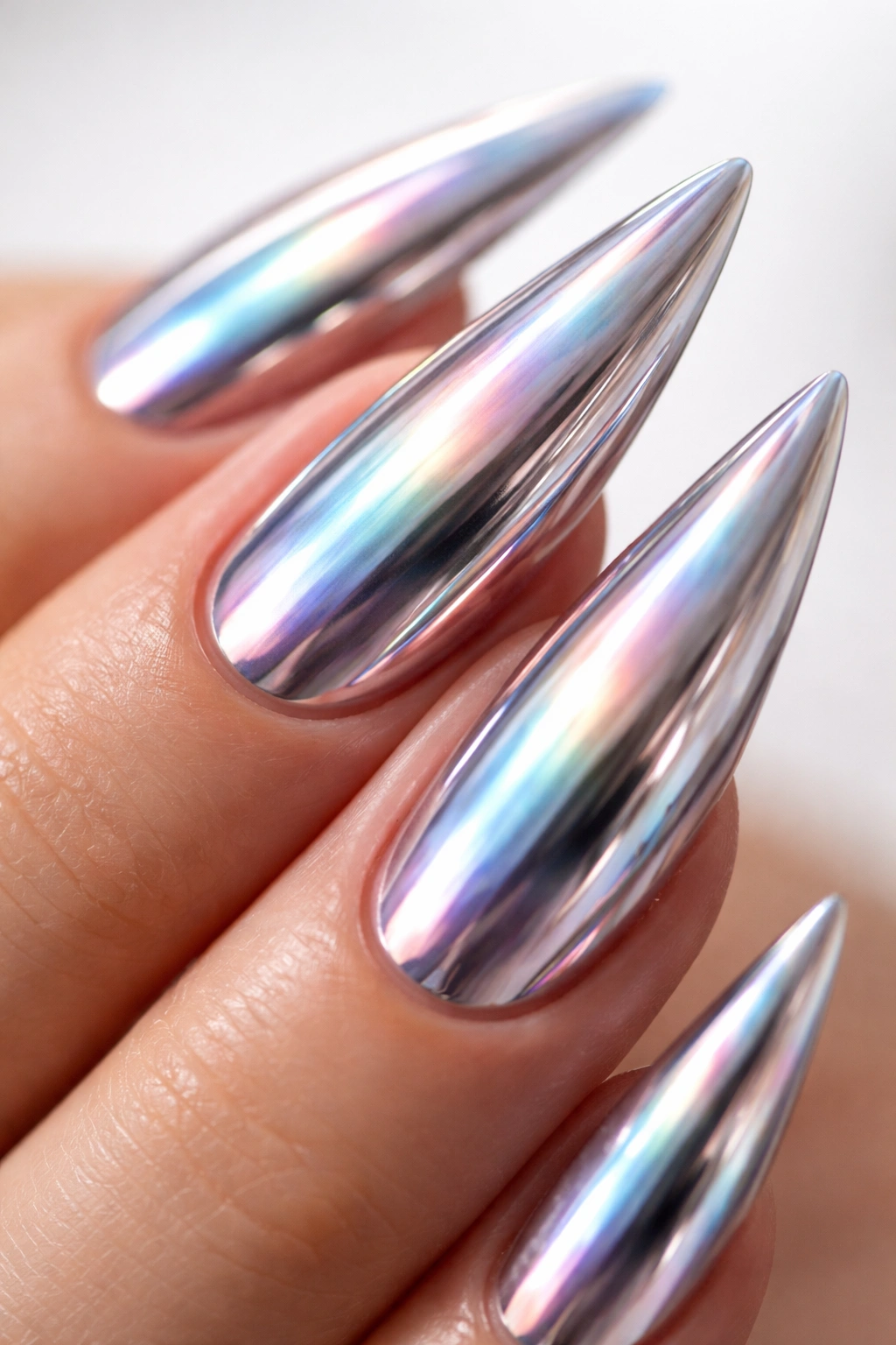 Chrome mirror stiletto nail with iridescent color shift under studio lights