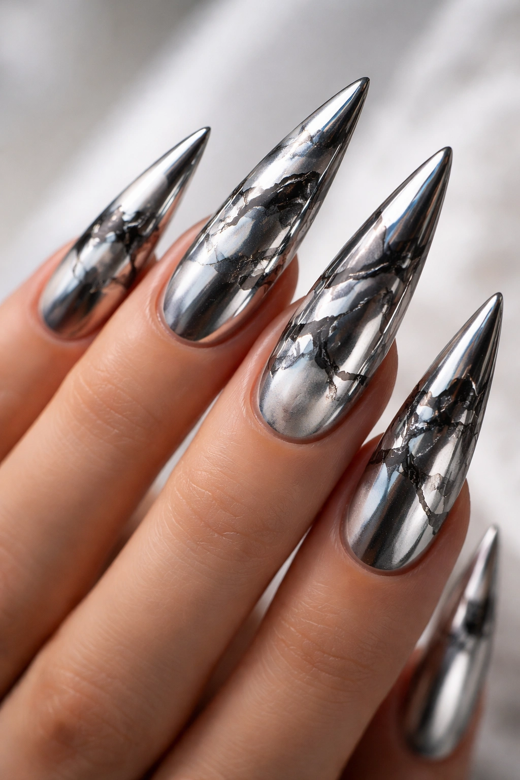 Stiletto nails with chrome mirror finish and marble veining.