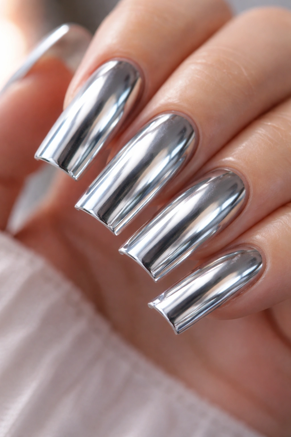 Close-up of slim duck nails with a chrome mirror finish reflecting light