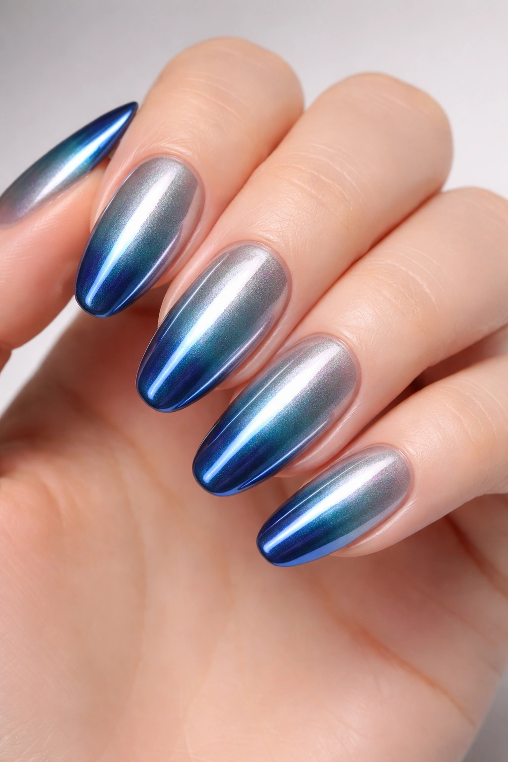 Long oval nails featuring a silver-to-blue chrome ombré gradient
