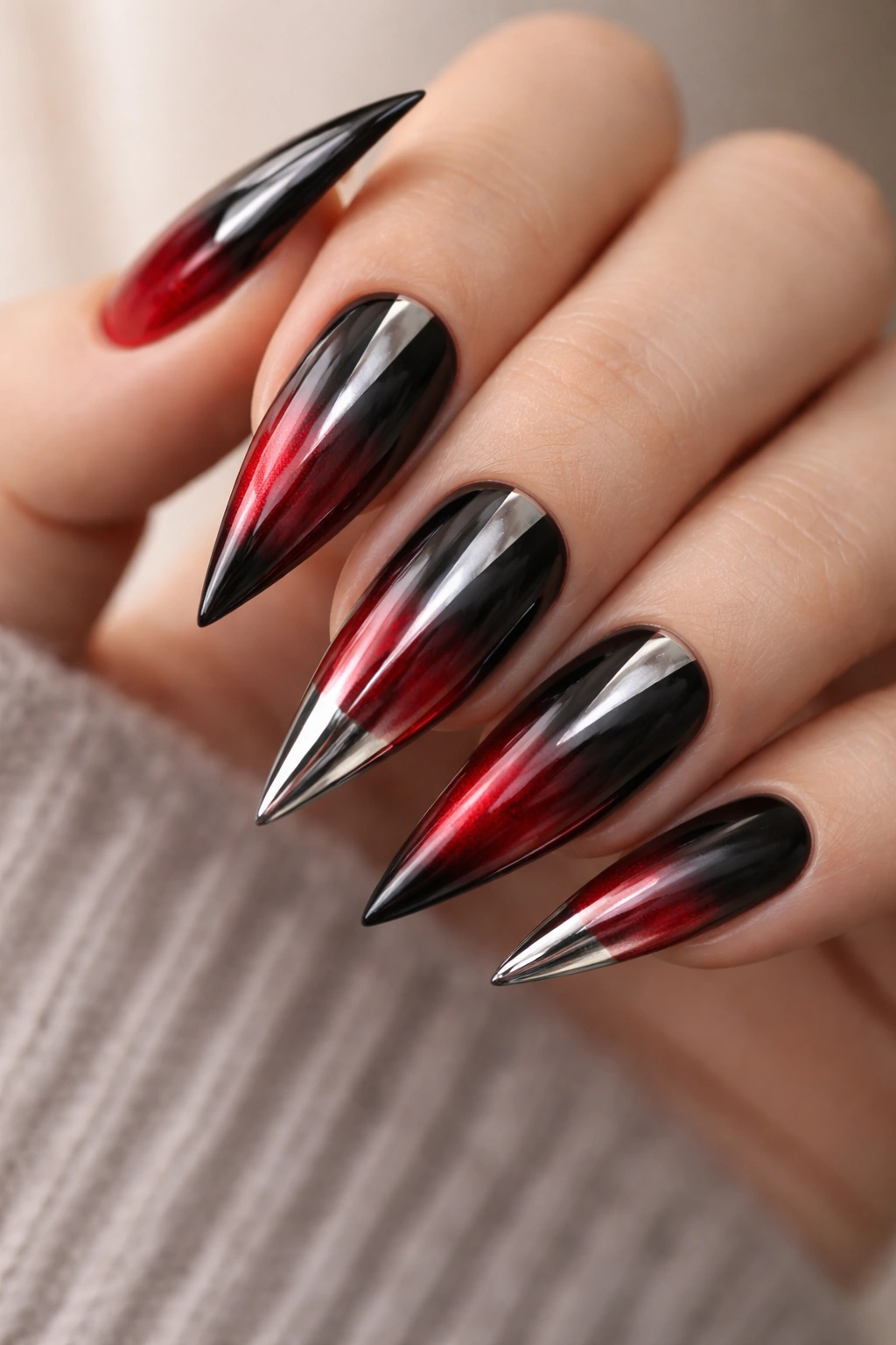 Close up of black-to-red ombre nails with chrome accents
