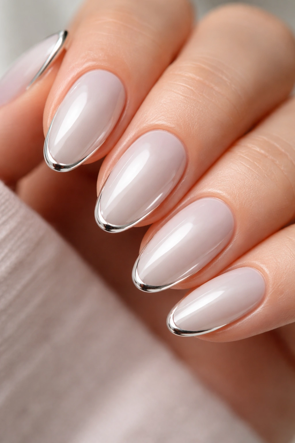 Close-up of short almond nails with a thin chrome outline