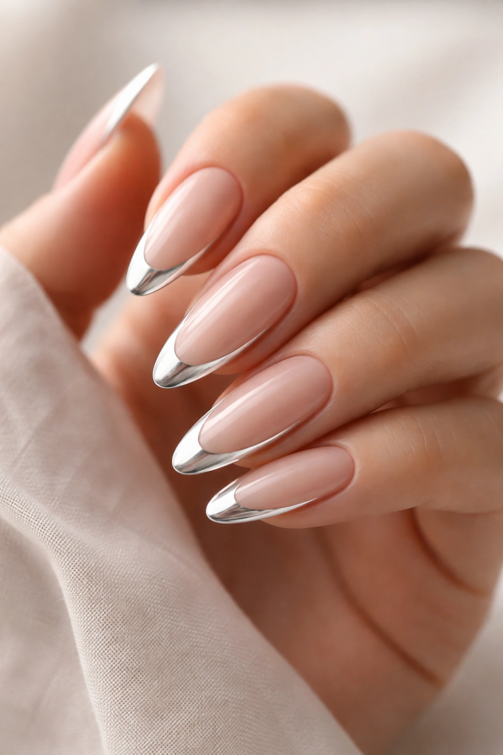 Almond nails with chrome-outlined French tips on a warm nude base.