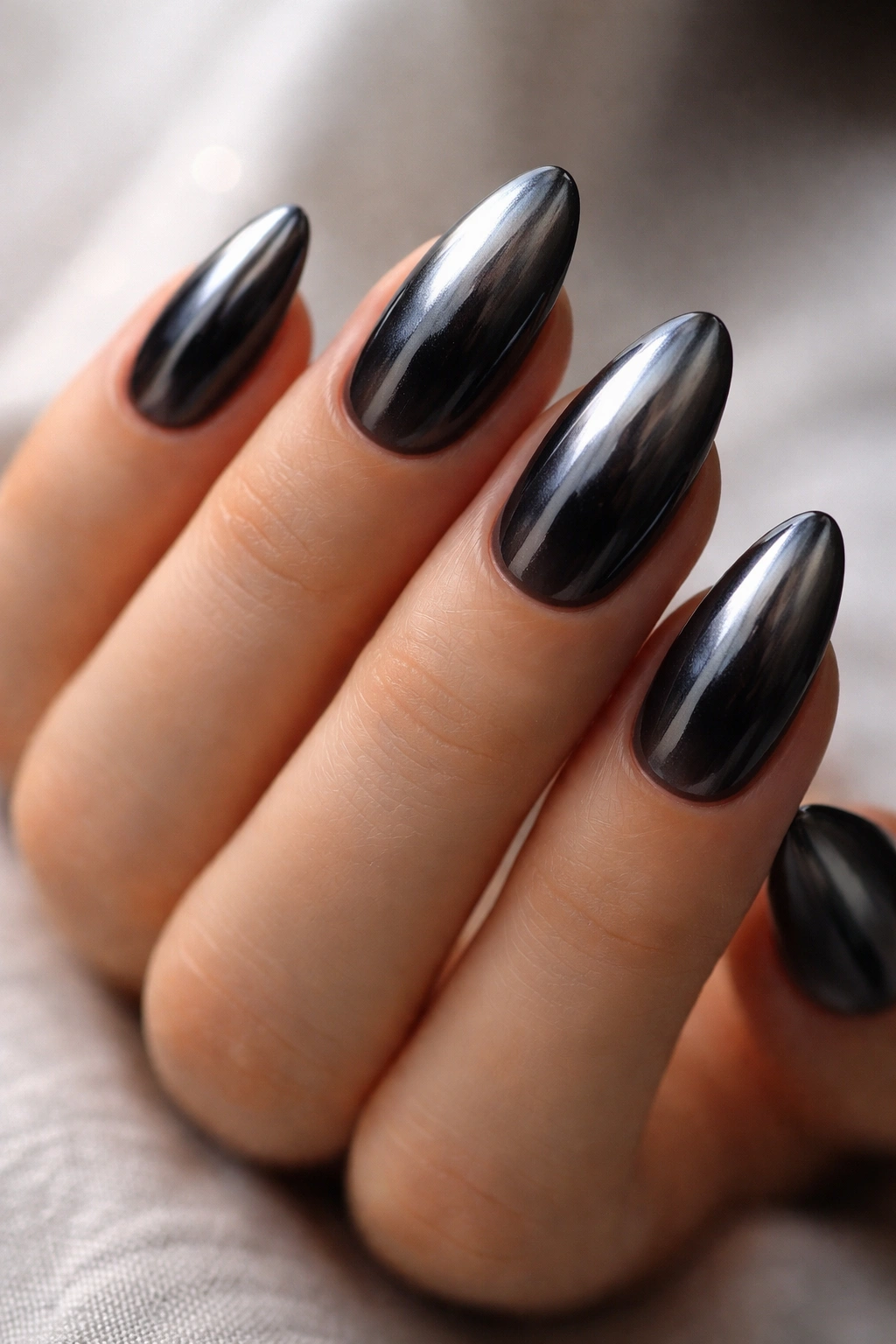 Almond nails with black ombre and chrome overlay for metallic look