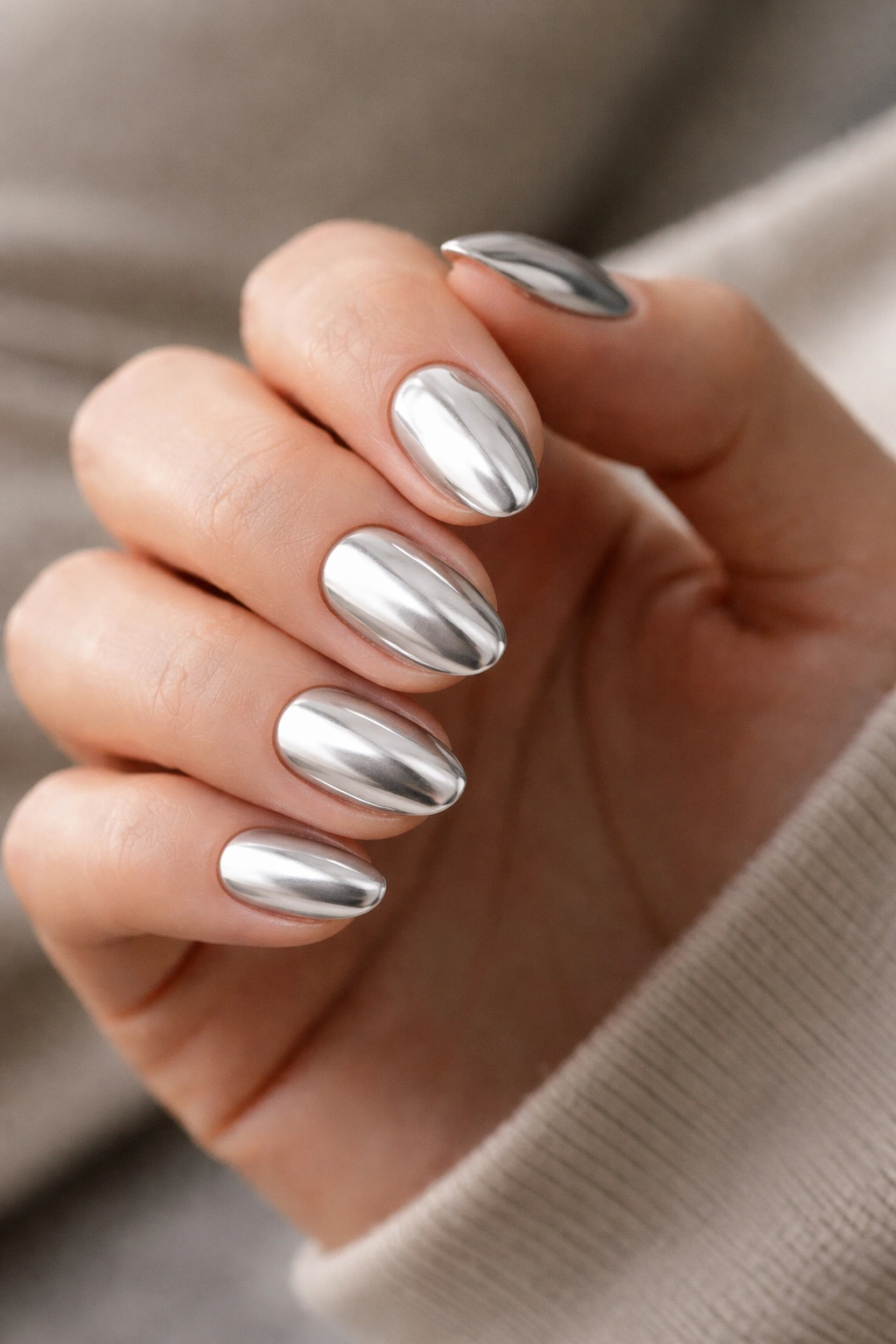 Close-up of pale silver chrome short almond nails