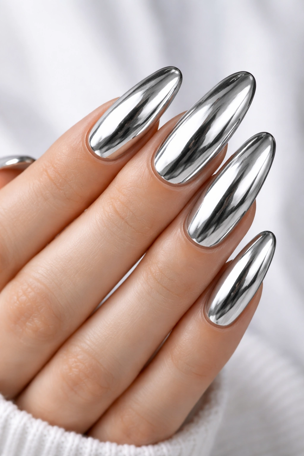 Close-up of chrome silver long oval nails with mirror finish and reflections