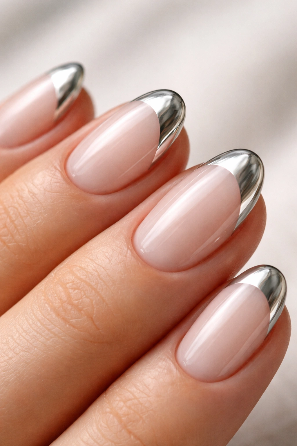 Close-up of a short oval nail with silver chrome tip on pale milky base showing soft contrast