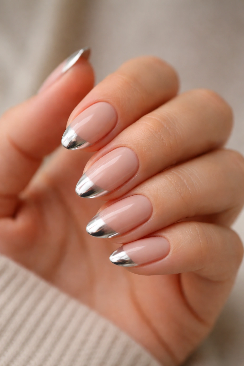 Close-up of short almond nails with chrome tips along the edge