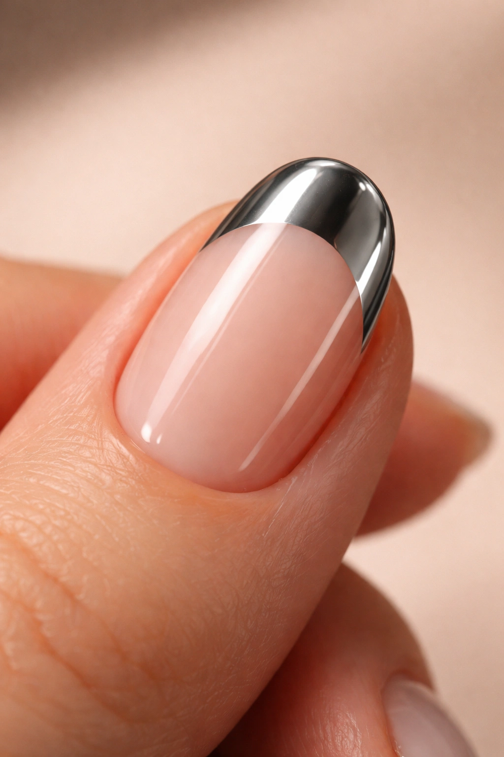 Close-up of a single short oval nail with mirror chrome tip on clean base