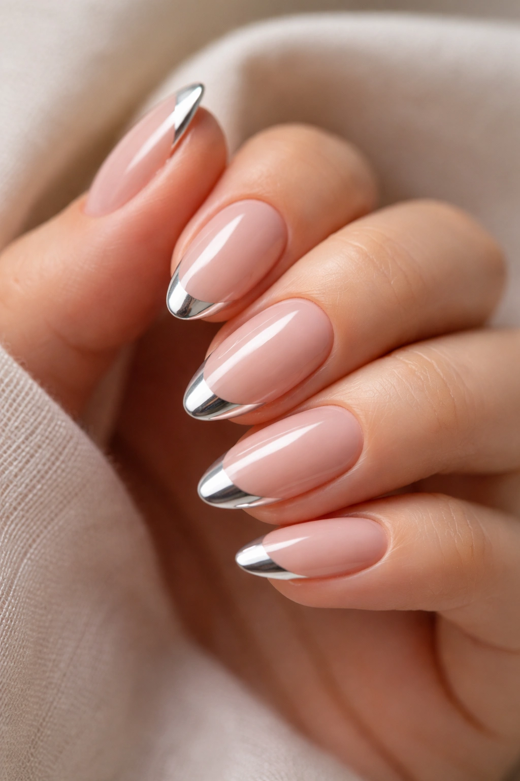 Close-up of short almond nails with a slim chrome tip on a nude base