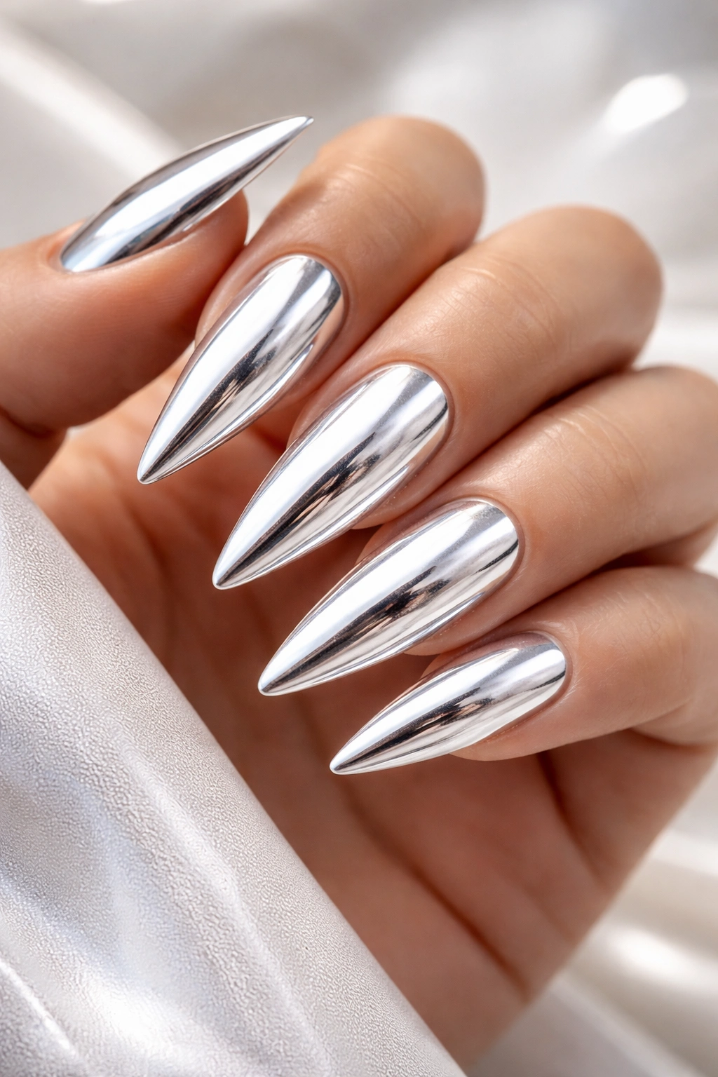 Close-up of stiletto nails with chrome white metallic finish reflecting light