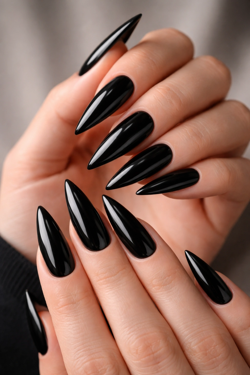 Close-up of hands with classic solid black stiletto nails in glossy finish