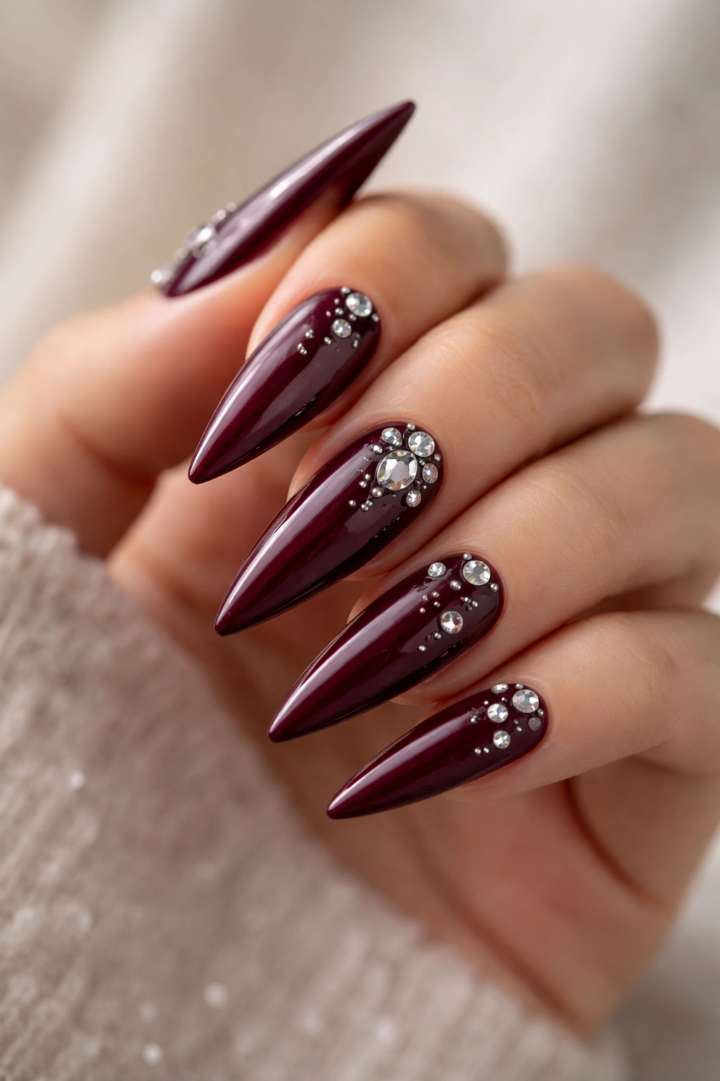 Burgundy stiletto nails with scattered diamond rhinestones