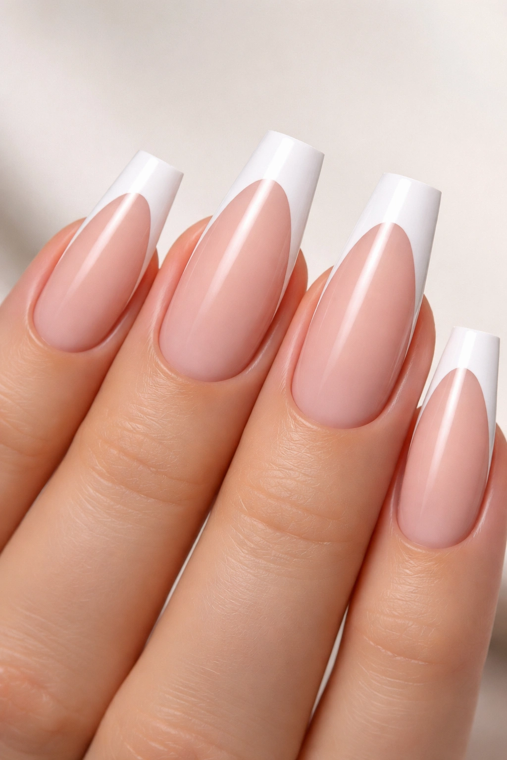 Coffin nails with nude base and white tips on a neutral background