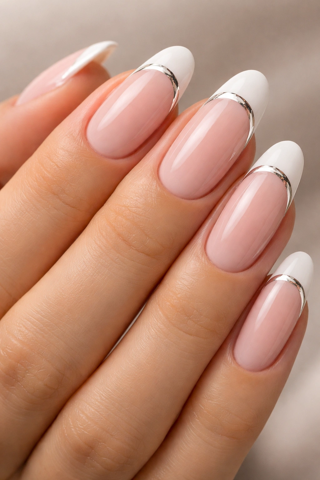 Close-up of long oval nails with nude-pink base and white tips in a modern French manicure.