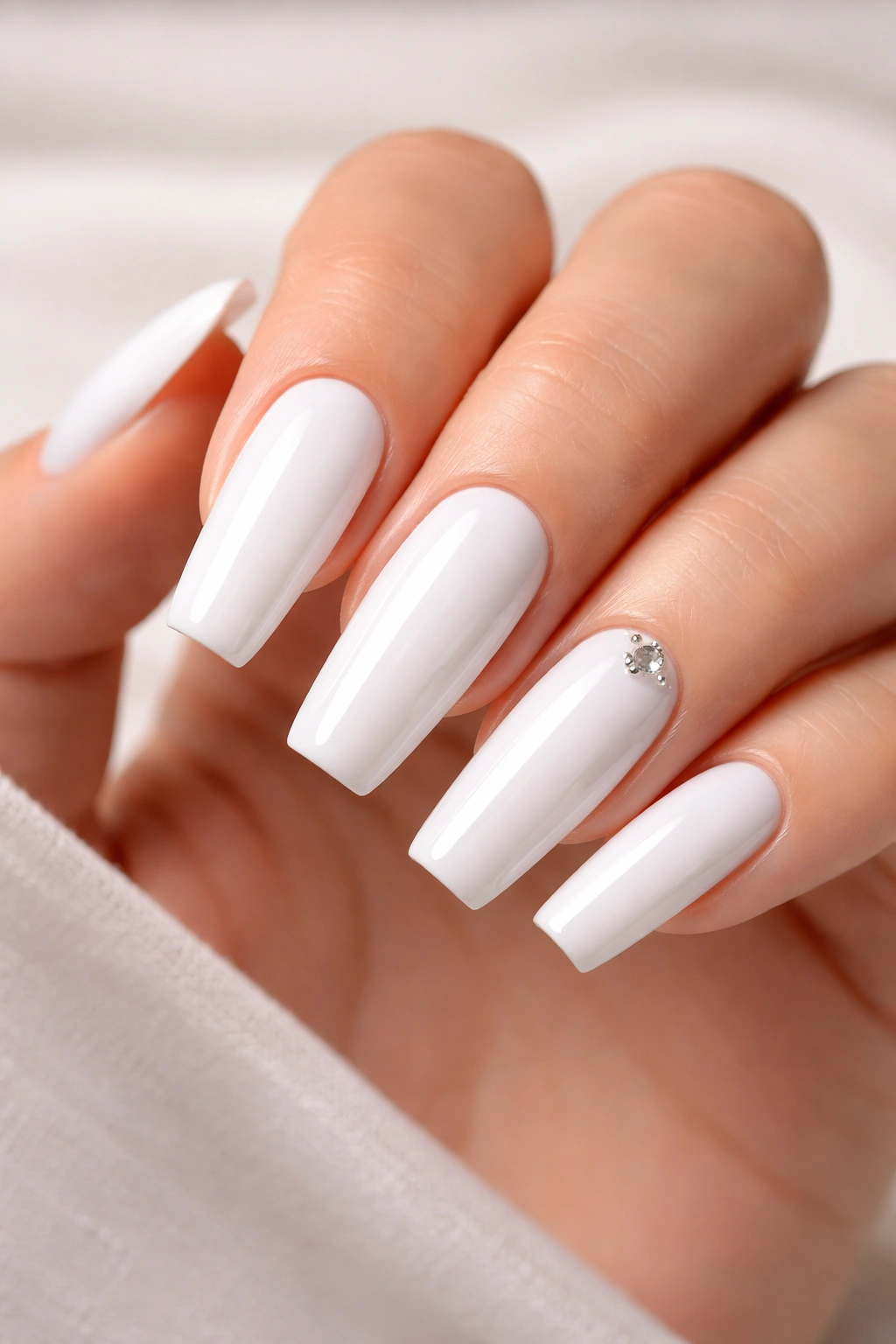 Close-up of classic white acrylic nails with a glossy finish.