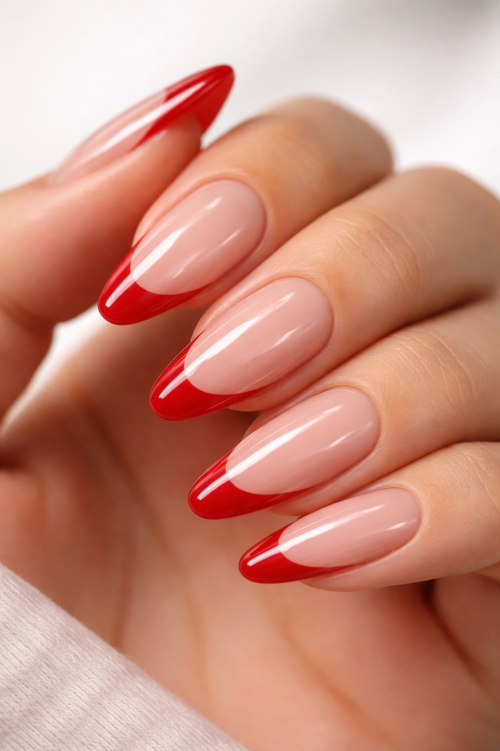 Close-up of almond nails with clear gel base and red tips