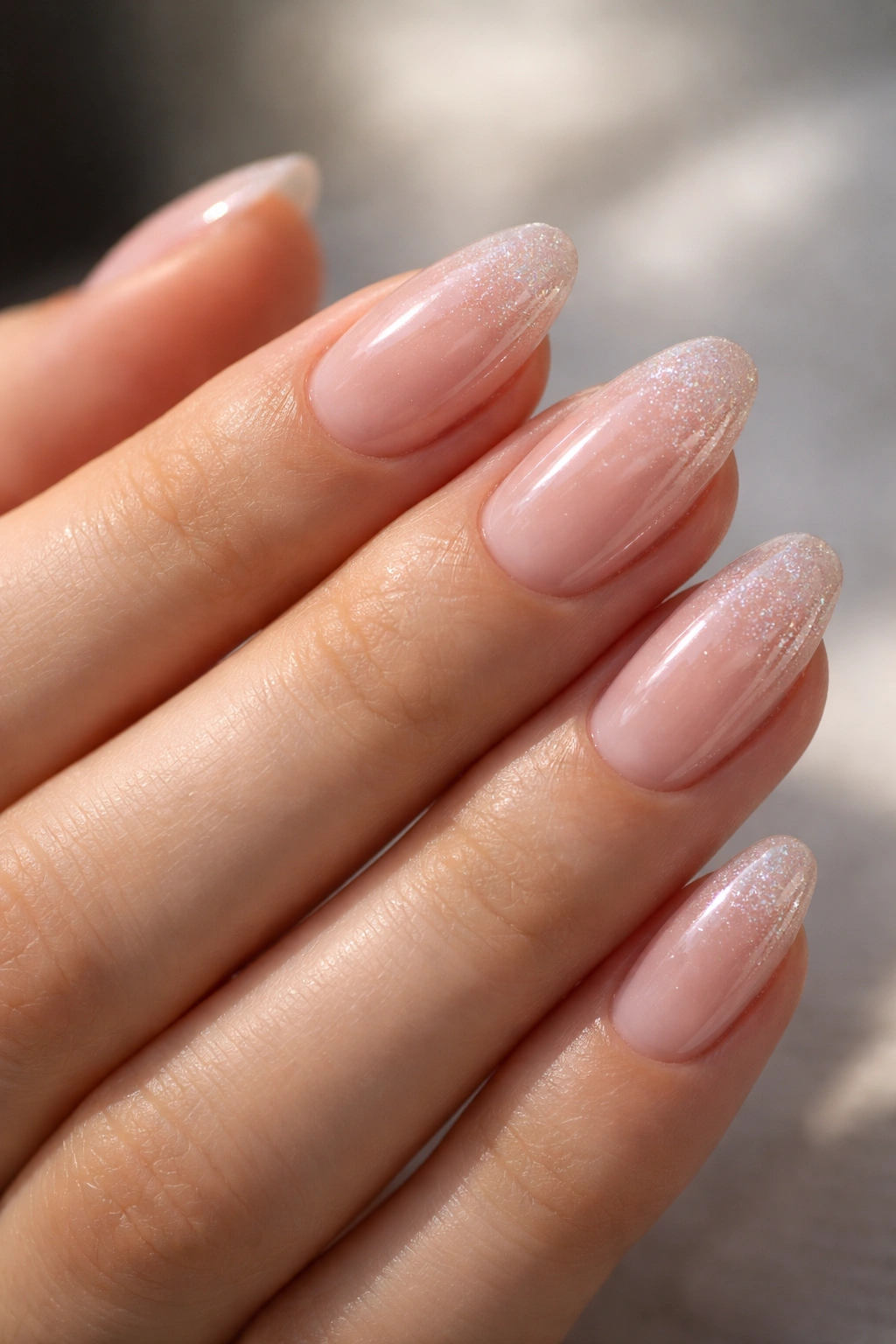 Close-up of clear gloss nails with micro-shimmer on short almond nails.