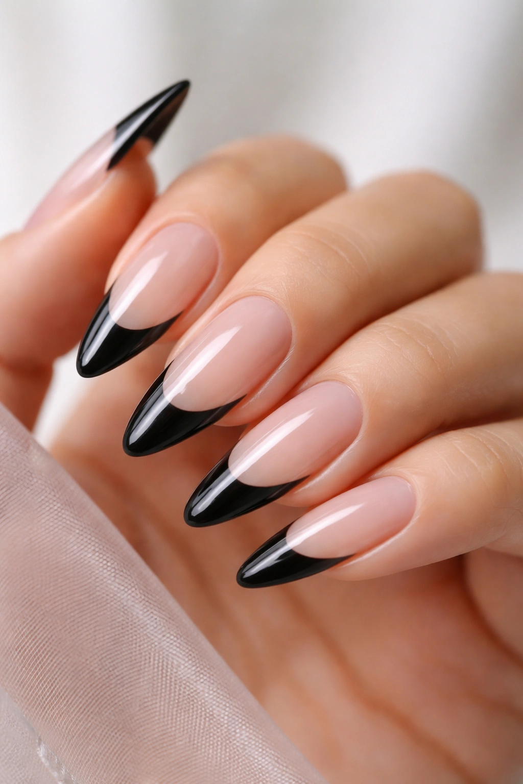 Close-up of long almond nails with black tips on a clear jelly base.