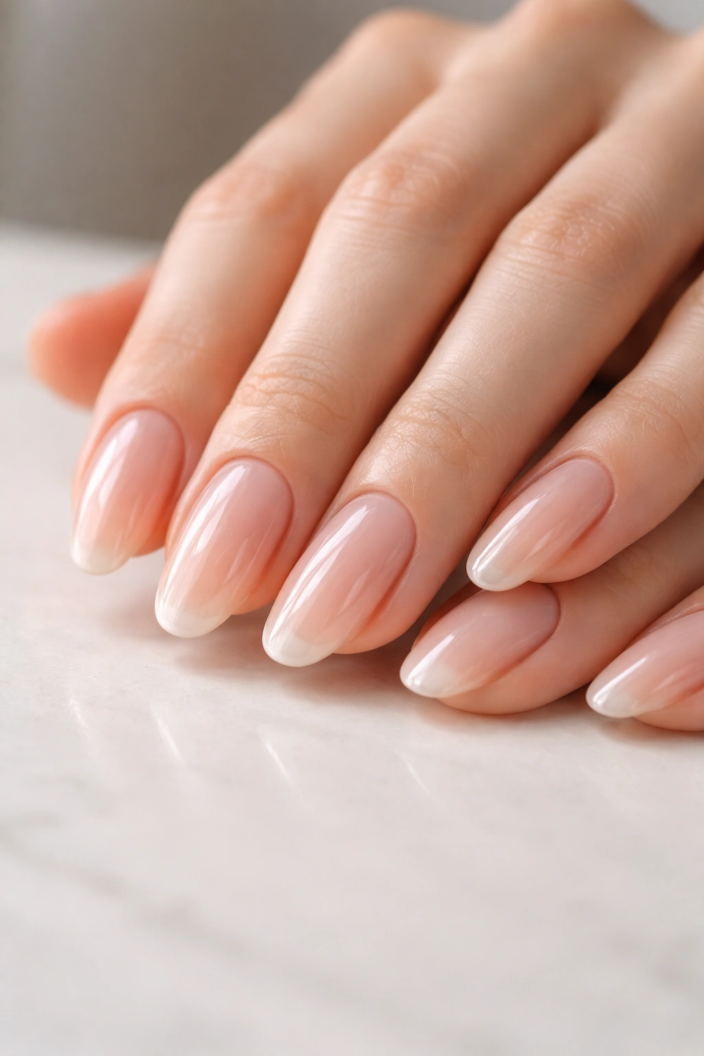 Close-up of long oval nails with clear glossy polish on buffed nails