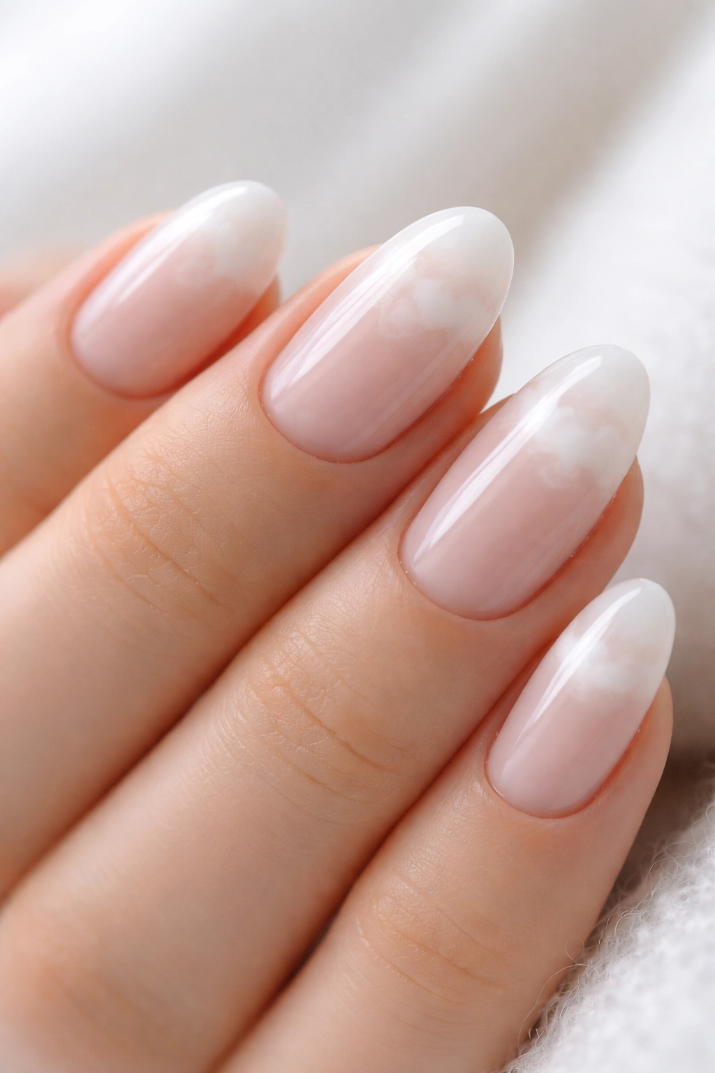 Close-up of sheer white cloud nails on extra-short almond nails with a milky base