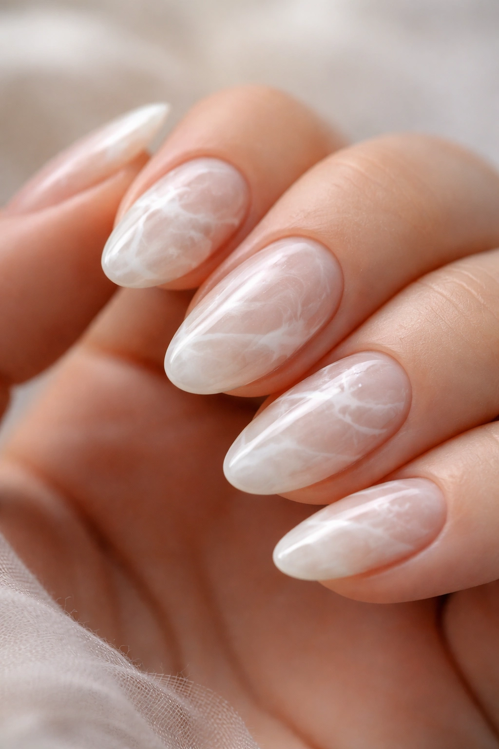 Close-up of cloudy marble with blended white swirls on short almond nails