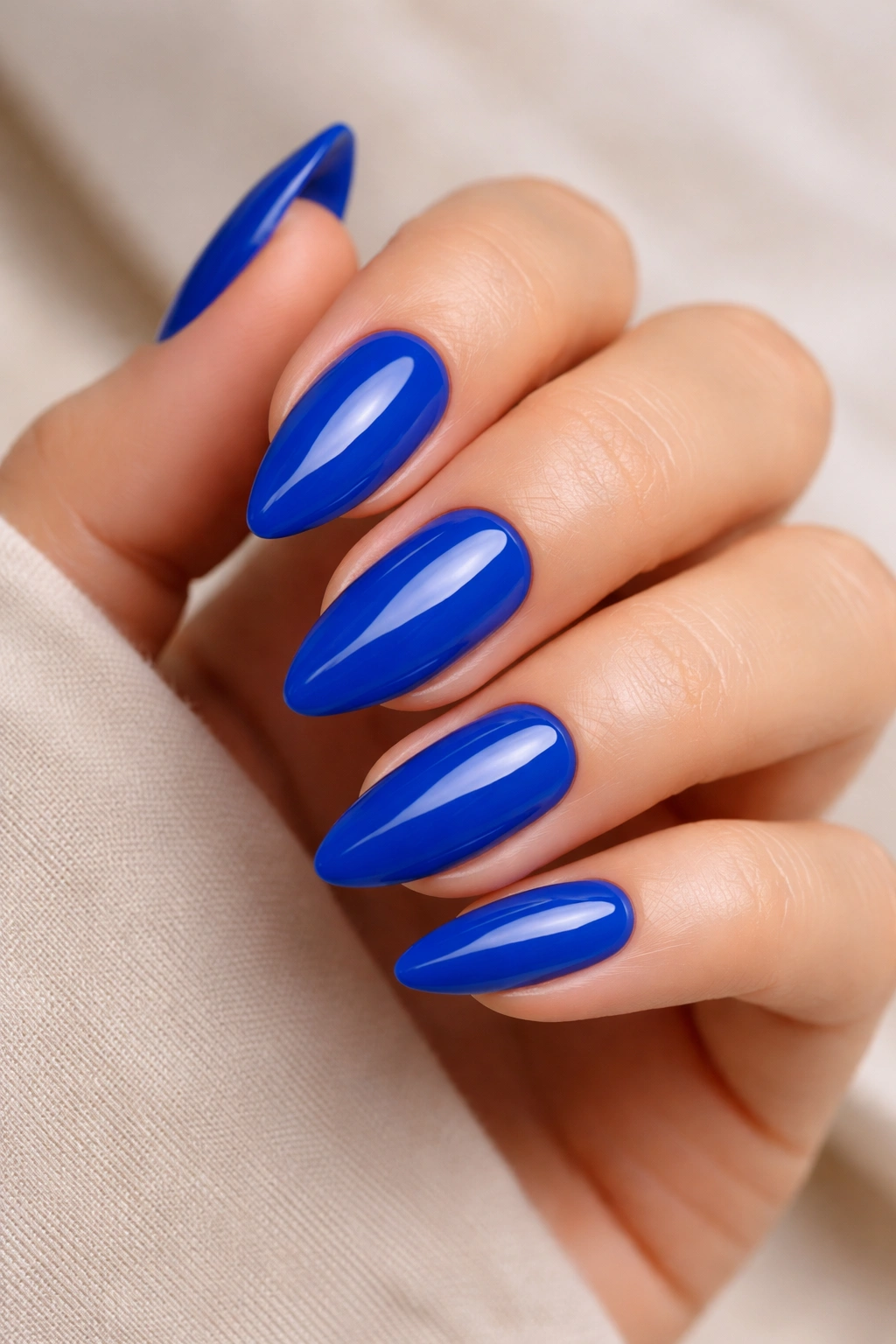 Close-up of cobalt blue almond nails with glossy finish