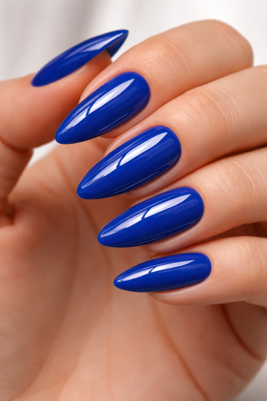 Close-up of cobalt blue almond nails with crisp edges and shiny finish