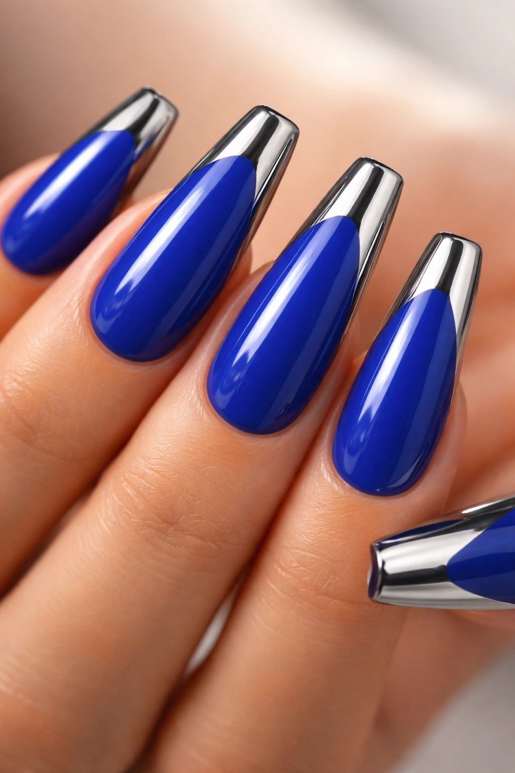Cobalt blue coffin nails with metallic chrome tips on a plain background