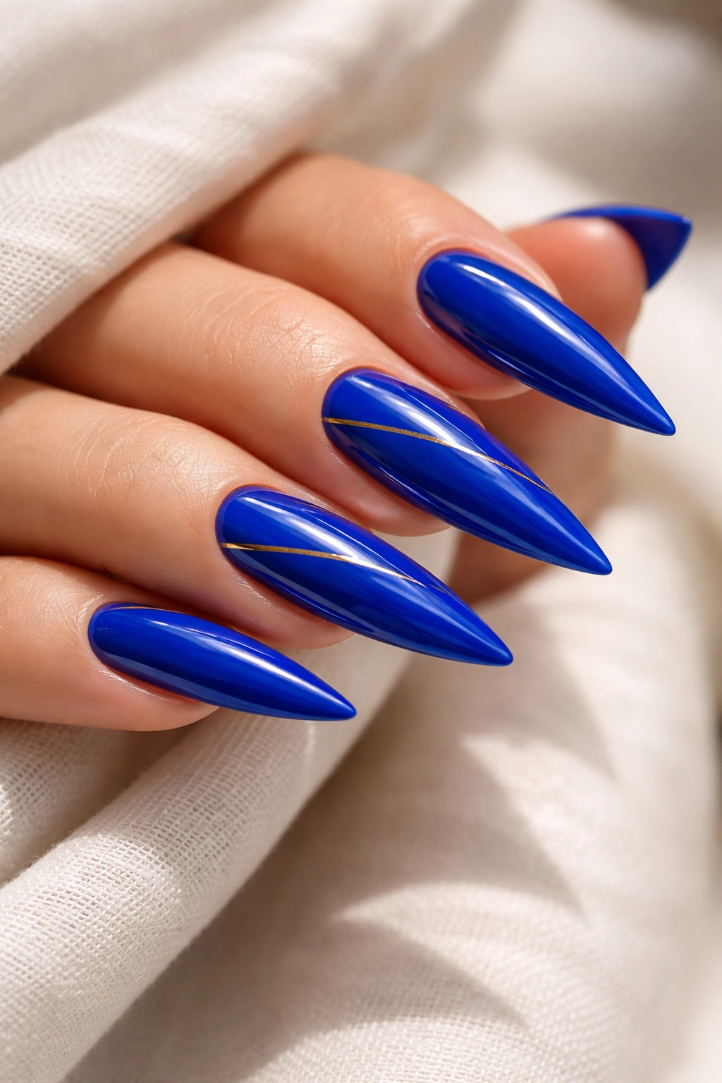 Cobalt blue stiletto nails with a subtle gold accent