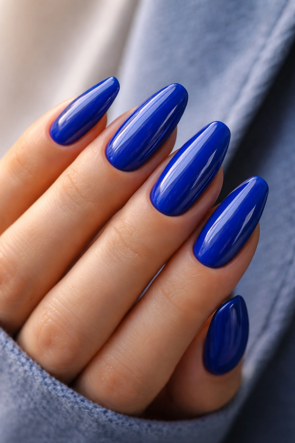 Close-up of cobalt blue nails with glossy finish on a neutral background