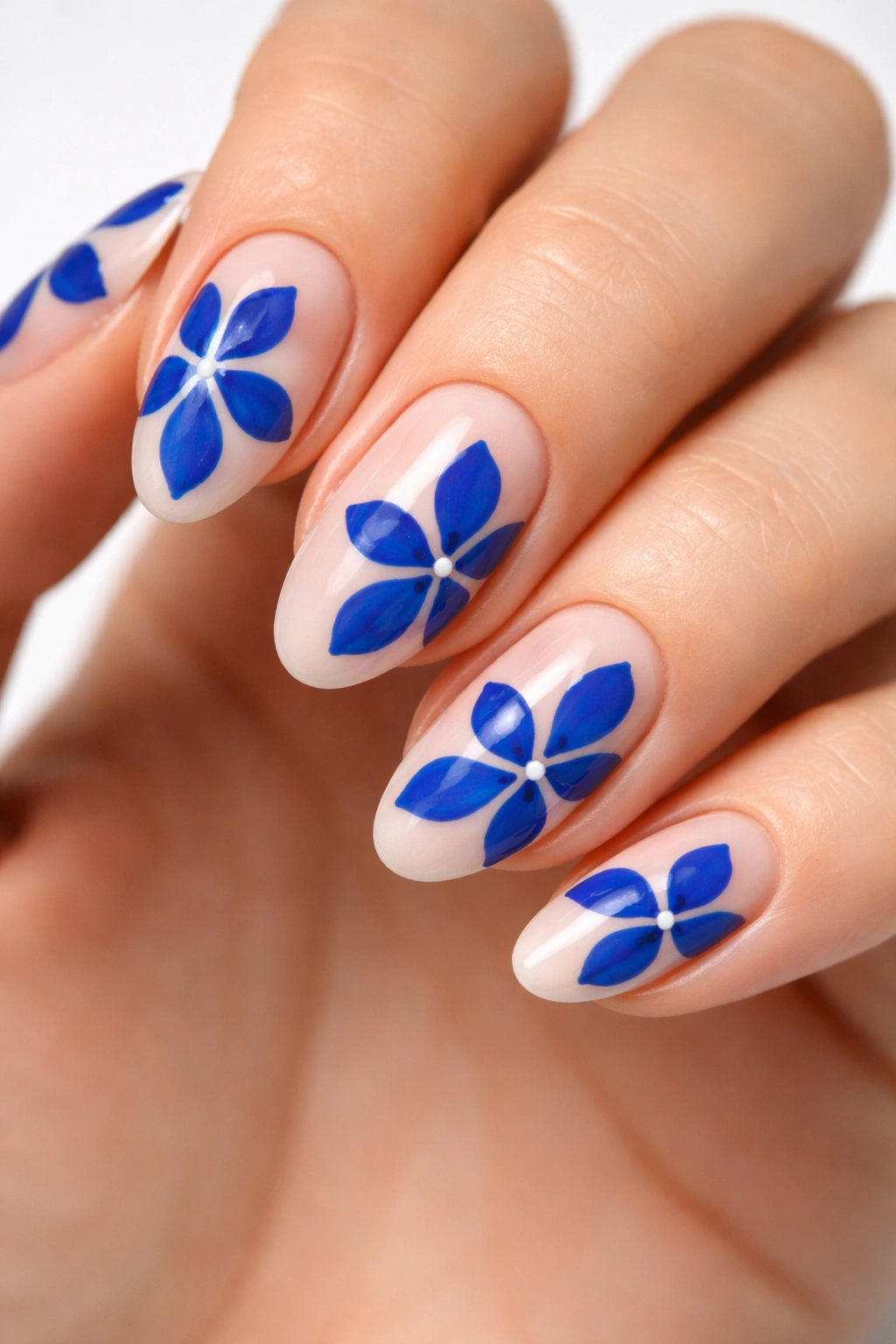 Close-up of cobalt blue petals on bare nude almond nails